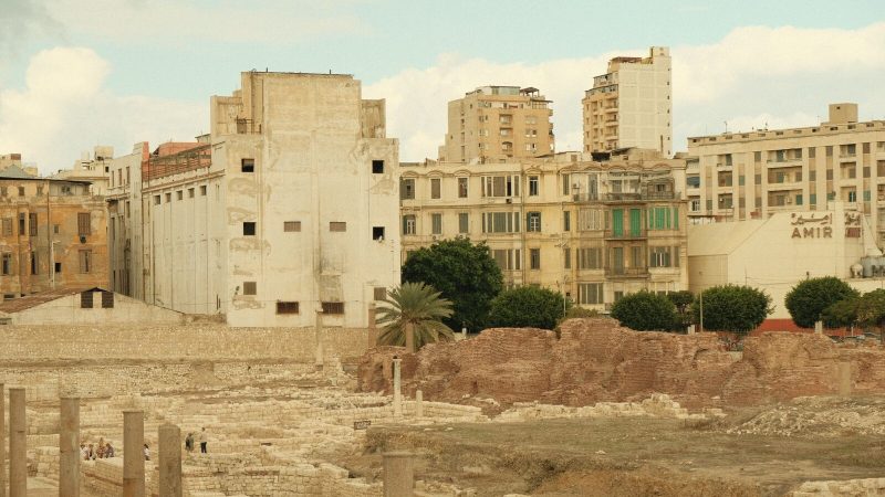 View of ancient Roman ruins against a modern urban backdrop, capturing history's blend with contemporary architecture.