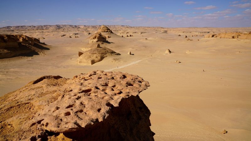 Expansive desert landscape in Egypt with unique rock formations and clear blue sky.