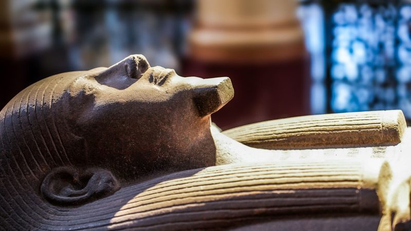 Close-up of an ancient Egyptian sarcophagus on display in a museum, showcasing intricate details.