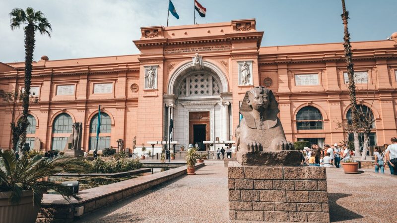 Low angle of aged building of Egyptian Museum located in Cairo with arched doorway and ancient statues in yard