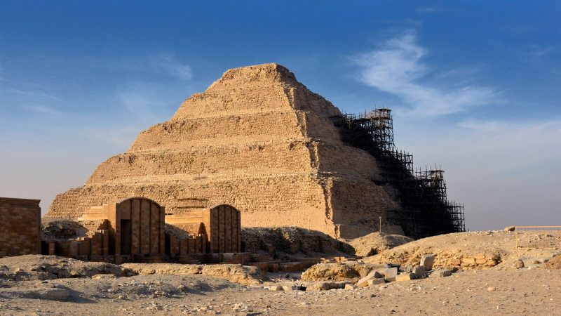 Step Pyramid of Djoser in Saqqara under restoration with clear blue sky.