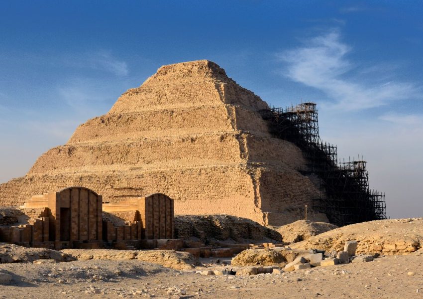 Step Pyramid of Djoser in Saqqara under restoration with clear blue sky.