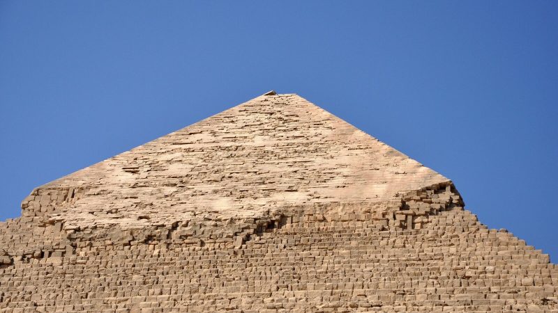 Close-up of an ancient Egyptian pyramid against a clear blue sky, showcasing its monumental architecture.