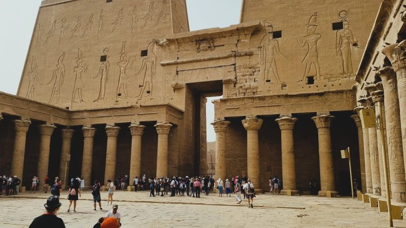 Visitors exploring the ancient Temple of Horus in Edfu, Egypt with rich hieroglyphs and architecture.