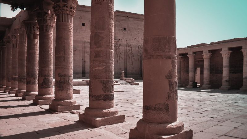 Majestic columns in an ancient Egyptian temple courtyard, Aswan, showcasing intricate carvings.