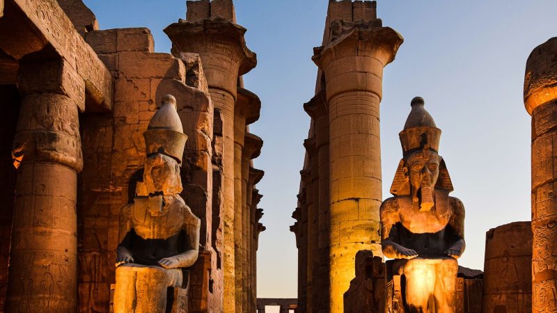 Illuminated statues and columns at Luxor Temple during sunset in Egypt.