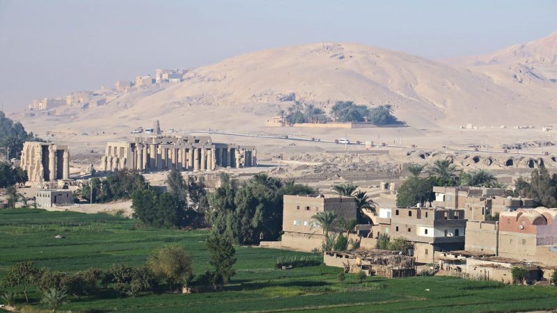 Breathtaking view of Luxor Temple amid lush greenery and desert hills in Egypt.