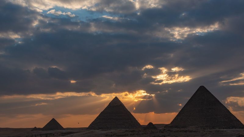 The Pyramids of Giza during a stunning golden hour sunset, capturing iconic silhouettes.