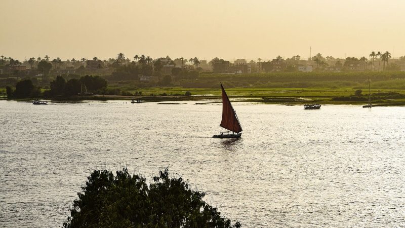 A traditional sailboat glides on the Nile River in Luxor, Egypt, as the sun sets.