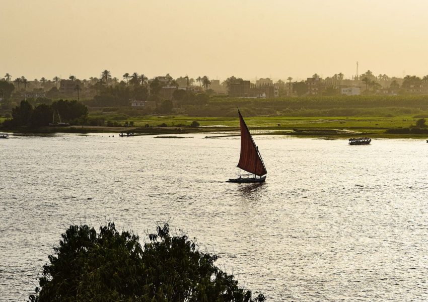 A traditional sailboat glides on the Nile River in Luxor, Egypt, as the sun sets.