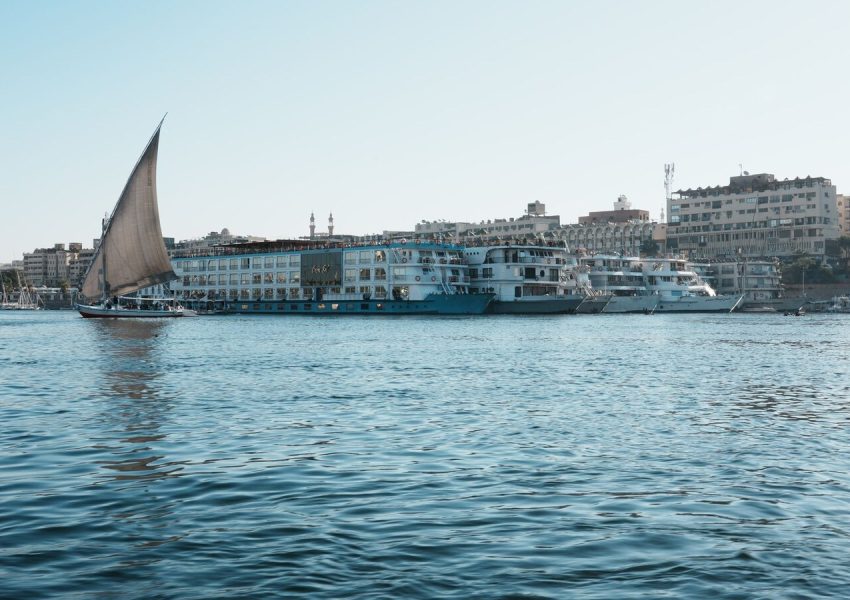 A picturesque view of a traditional sailboat on the Nile River near city waterfronts.
