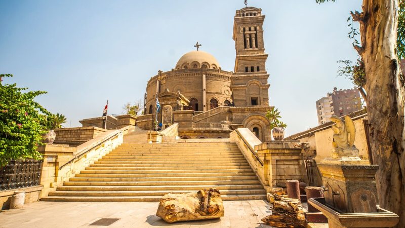 Exterior view of the historic St. George's Church in Cairo, showcasing its iconic tower and grand entrance stairs.