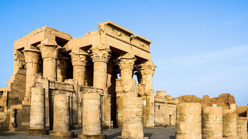 Explore the stunning ancient Egyptian temple ruins featuring iconic columns under a clear blue sky.