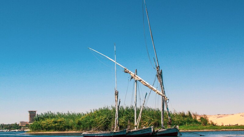 Scenic view of traditional boats docked on a tranquil river with clear blue sky.