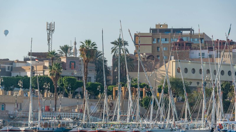 Sailboats moored in Luxor's marina against historic architecture.