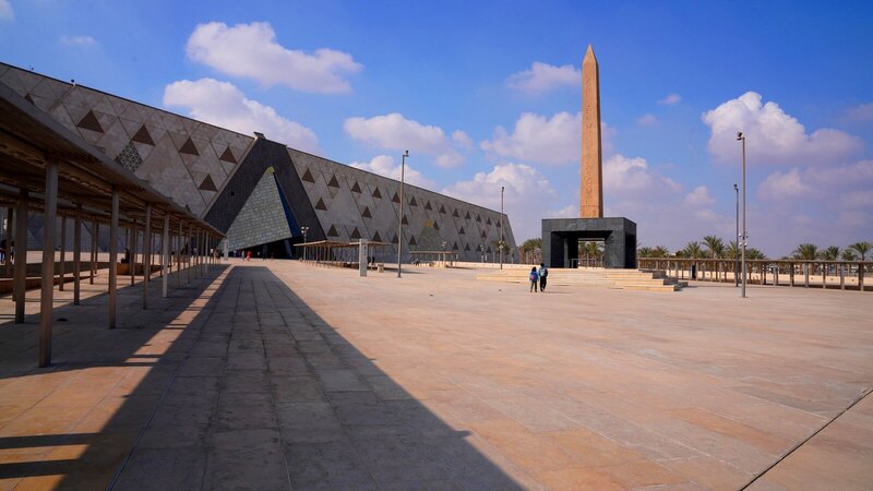 Wide-angle view of the Grand Egyptian Museum with a prominent obelisk and clear skies.