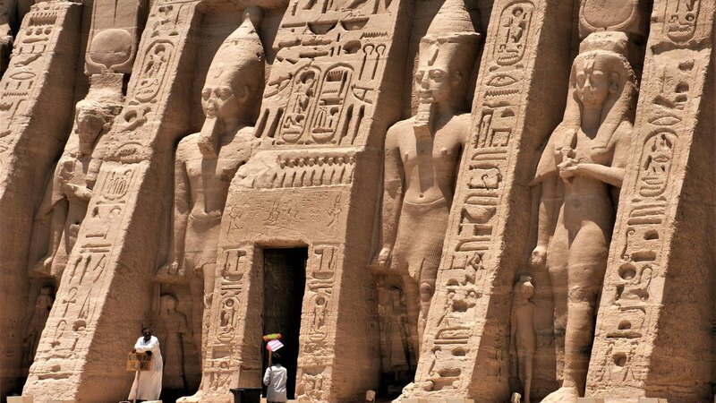 Exterior view of an ancient Egyptian temple featuring hieroglyphics and carved statues.