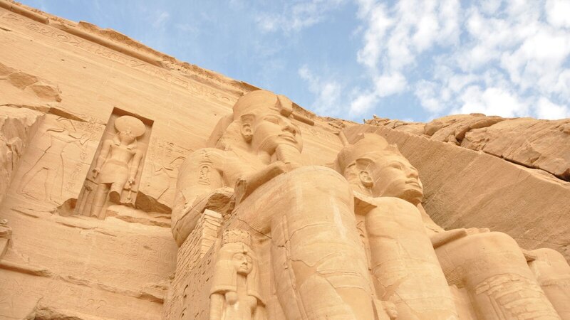 Ancient sandstone statues of pharaohs at Abu Simbel, Egypt, under a clear blue sky.