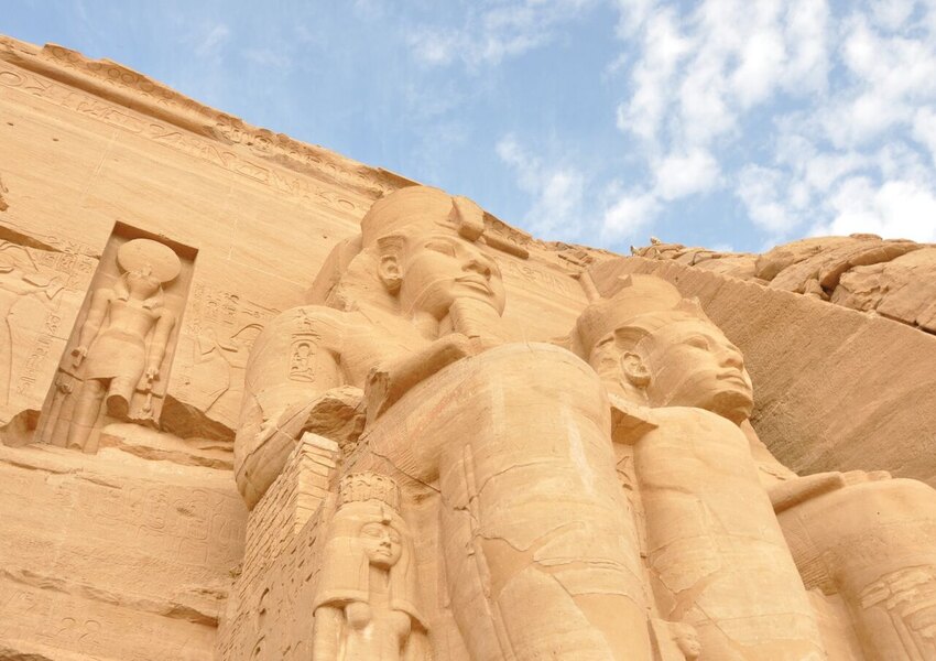 Ancient sandstone statues of pharaohs at Abu Simbel, Egypt, under a clear blue sky.