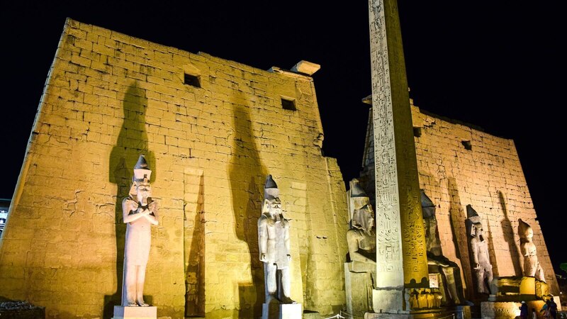 Night view of illuminated ancient statues and obelisk at Luxor Temple, Egypt.