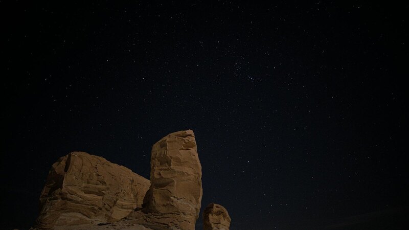 A night view of natural rock formations under a starry sky at Siwa Oasis in Egypt.