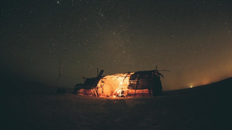 A serene night in Egypt's desert, capturing a starry sky and a warmly lit tent under the Milky Way.