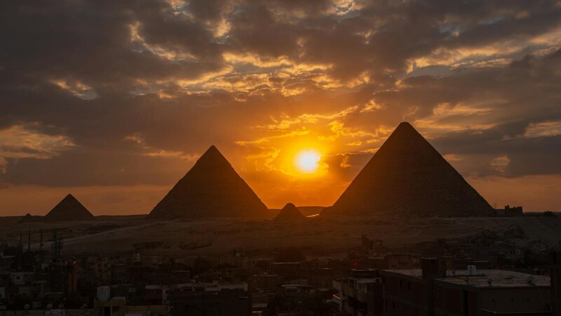 Silhouette of the Giza pyramids at sunset, capturing dramatic skies and ancient wonder.