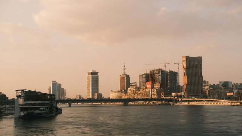 A scenic view of Cairo's skyline along the Nile River at sunset, capturing the city's modern architecture.
