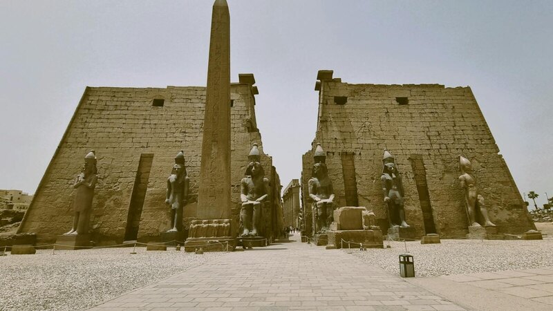 A captivating view of the ancient Luxor Temple with towering obelisks and statues under a clear sky.