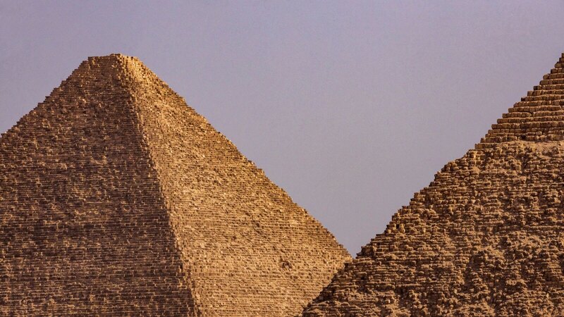 A close-up view of two iconic Egyptian pyramids under a clear blue sky.