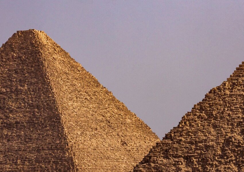 A close-up view of two iconic Egyptian pyramids under a clear blue sky.