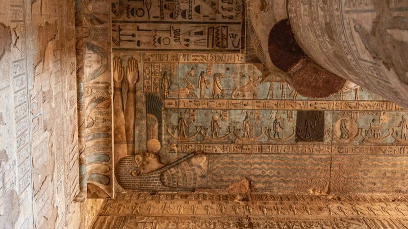 Detailed view of ancient Egyptian hieroglyphs and carvings on a temple wall depicting religious symbolism.