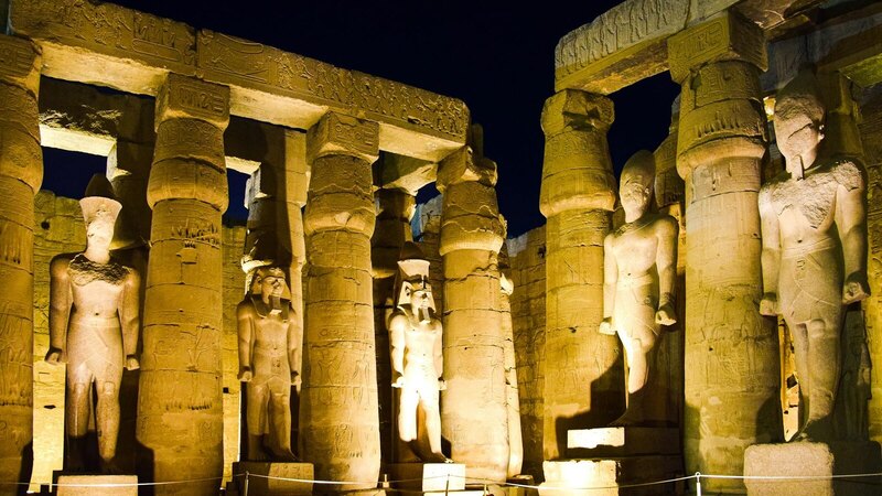 Night view of illuminated ancient statues at Luxor Temple, showcasing historical Egyptian architecture.