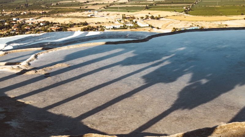A stunning aerial view of Pamukkale's travertine terraces in Turkey during the day with shadows and sunlight.